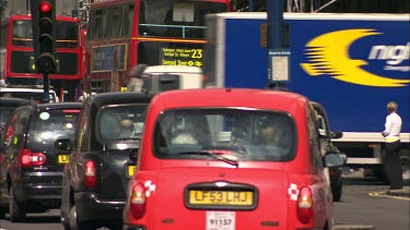 Busy London street scene with black and red taxi cabs and buses.