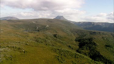 Aerial of Tasmania, green, mountains in distance. Wilderness area.