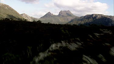 Aerial of Tasmania, forests, lake and mountains in distance. Wilderness area. Cradle Mountain in background.