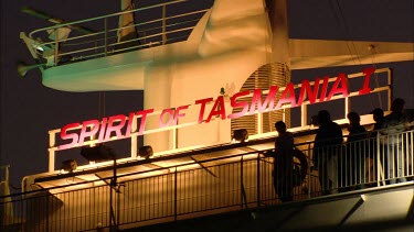 Passengers aboard spirit of Tasmania in evening, lights on. Lifeboats on side of ship.