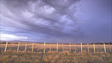 Dark clouds gather over field.