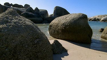 CU rocks boulders on beach, the waves crash gently around them.