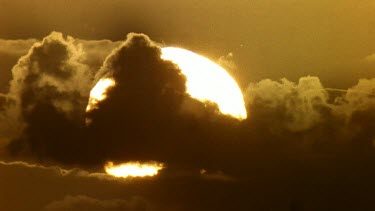 Sun setting through clouds close up