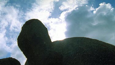 Low angle. Boulders and sun moving through clouds.