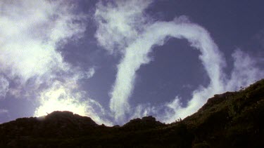 Cloud forming circular pattern as iti rises above mountain