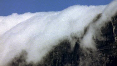 Thick cloud tumbling down over ridge of mountain