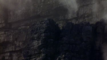 Veil of misty cloud flowing down over cliff