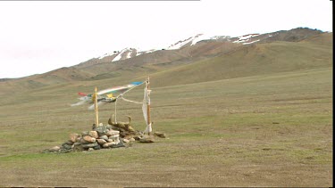 Prayer flag flutter over Tibetan Buddhist shrine, Chang Tang Plateau, Tibet. Yak like skull over shrine.