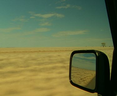 Driving in outback, reflection of desert in car mirror. Cattle, road bus 4 wd four wheel drive Big open sky clouds horses