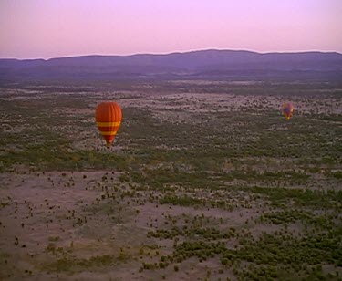 Hot-air balloons flying over desert.