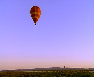 Hot-air balloons flying over desert.
