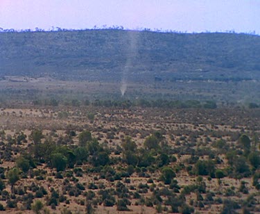 Desert scenes. Dust devil small tornado whirling in distance. Red earth and scrub
