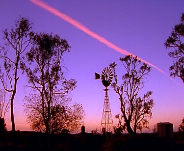 Early morning sunrise sunset with windmill. Line of pink clouds in sky.
