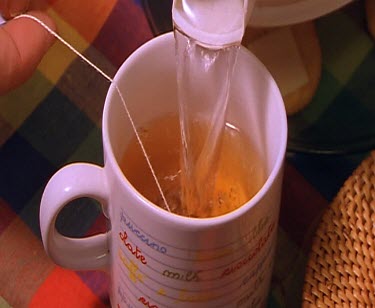 Pouring water into mug with tea bag