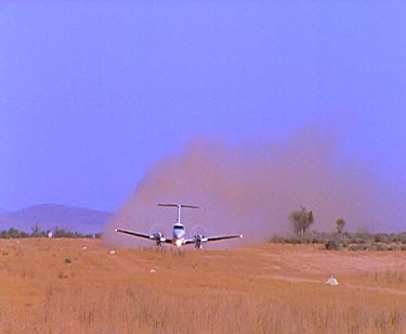 Light propeller plane take-off in field, dust