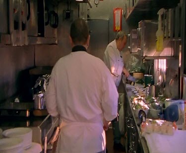 Chefs cooking in train galley kitchen. Wobbly shot because of train motion