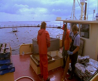 Fishermen on board loading nets into hold