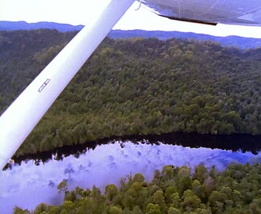 Franklin River. Reflections of clouds on still water. Flying down the rivers meander. Thick rainforest on banks of river.
