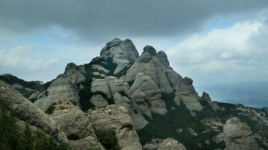 Set high on Mt Montserrat, sunlight sprinkles light on the eye-catching mountain side as the clouds roll by. Mt Montserrat is a major tourist attraction in Spain.
