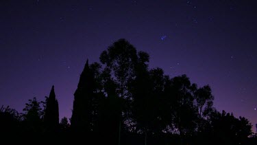 A timelapse of the night sky with brilliant purple hues and stars moving towards the dawn.