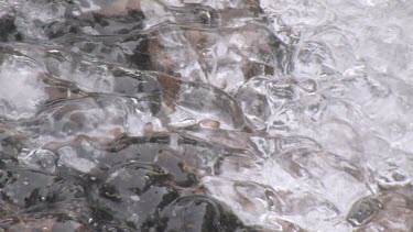 An icy streamlet runs down rocky slabs
