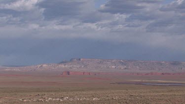 Big desert valley with distant mesas and storm filled sky