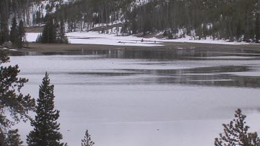 Wintry lake with in alpine setting surrounded by snowy banks