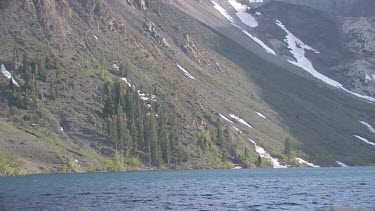 Rippling lake in alpine setting with mountain sweeping up from shoreline