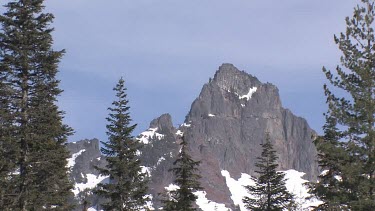 Jagged mountain peaks with snow framed through trees