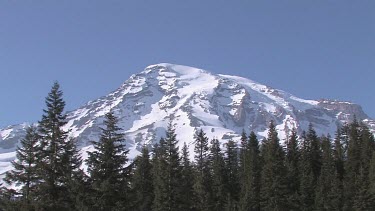 Mountain with snowy peak, blue sky and forest