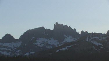 Jagged mountain peaks with snow at sunrise or sunset