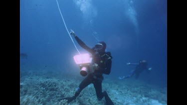 diver instructing, holding light in hand