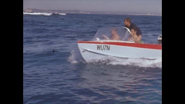 men in motor boat sail through shot