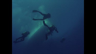 looking up three divers and boat on sea surface