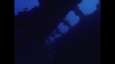 Diver swims past frame of wreck with light