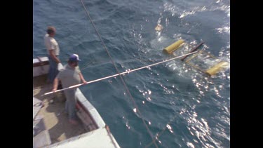 man pushes shark cage away from boat