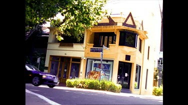 Low Angle. Exterior of a small art gallery in old Federation style building. A car passes.