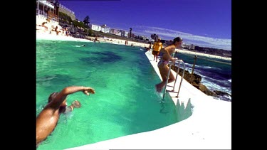 Swimmers in Bondi Icebergs swimming pool. Bondi lifesavers look on. Bondi Beach in background.
