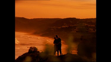 Couple kissing at sunset with ocean in background