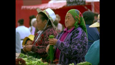 Women selling herbs and vegetables at a flea market