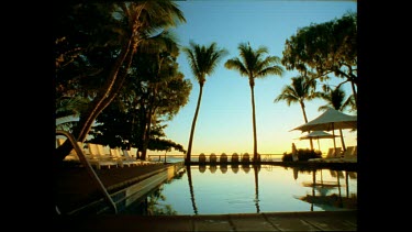 Hayman Island resort, sunrise. Woman walking along pool