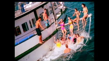 Young people having fun in water net along boat