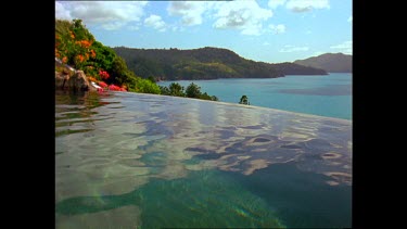 Girl swims across pool on Hamilton Island with sea and island in background