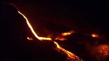 Active volcano steaming, Lava on side of vent, burning red hot. Night