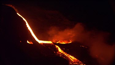 Active volcano steaming, Lava on side of vent, burning red hot. Night. Pan reveals lava flow that has recently solidified.