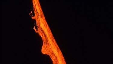 Active volcano. Lava flow. River of lava pouring down slope. Night.