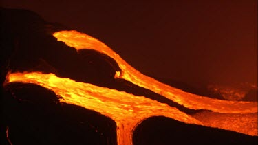 Volcano. Lava flowing down channel. Night. Lava flowing quickly.