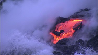 Lava flowing directly into ocean. Waves turning to seam.