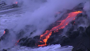 Lava flowing directly into ocean. Waves turning to seam.