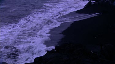 Waves crashing on black solidified lava beach.